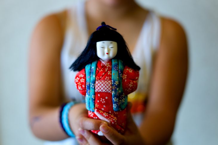 赤い衣装の日本人形を持つ人