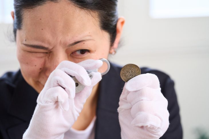 ルーペを使って古銭を鑑定する女性