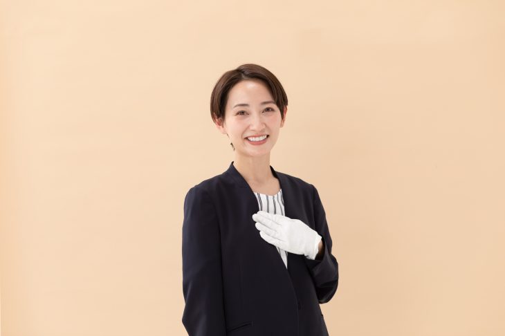 白い手袋をはめてほほ笑む女性の査定士