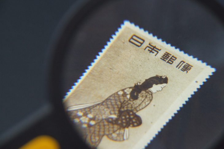 切手をルーペでチェックしている人