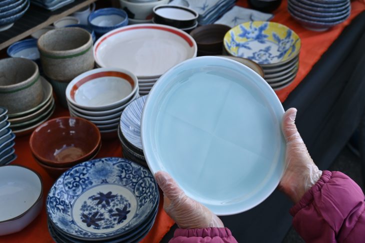 陶器製の食器を手に取る人