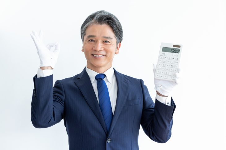 電卓を持ってOKサインを出す査定士の男性
