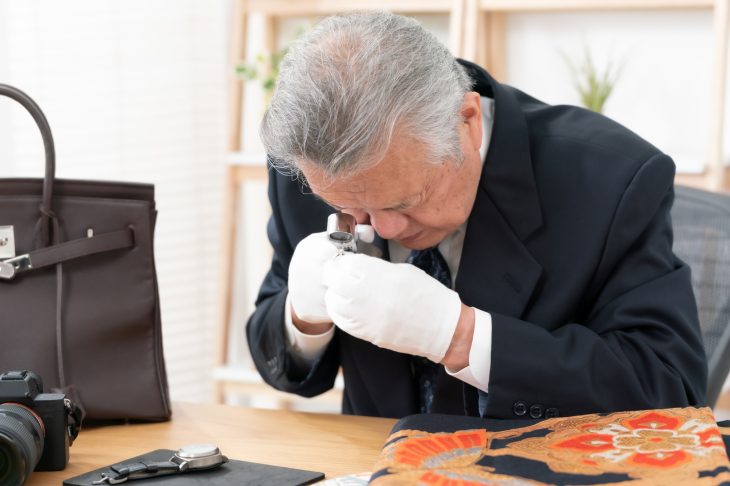 ルーペで鑑定をする男性