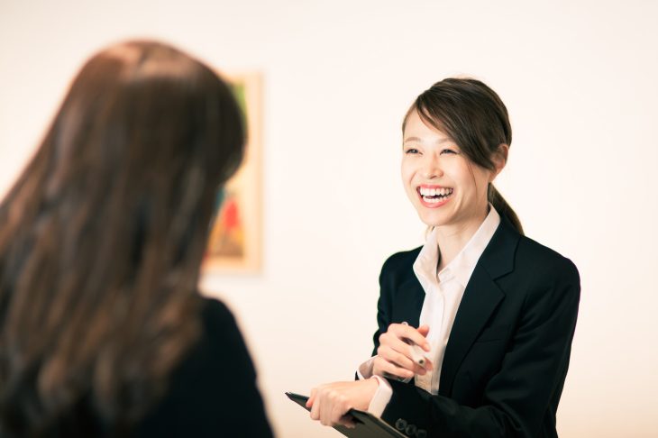 髪の長い女性と話をするスーツを着た笑顔の女性