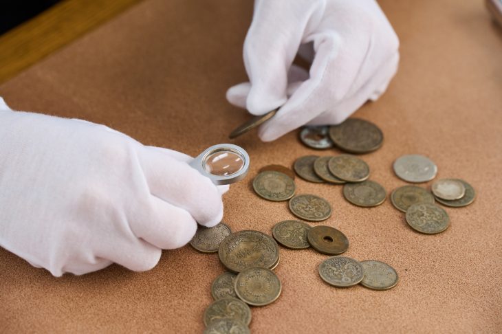 ルーペで古銭をチェックしている人の手元