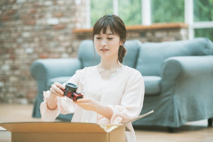 寿命を迎えたデジカメを段ボール箱に入れようとする女性