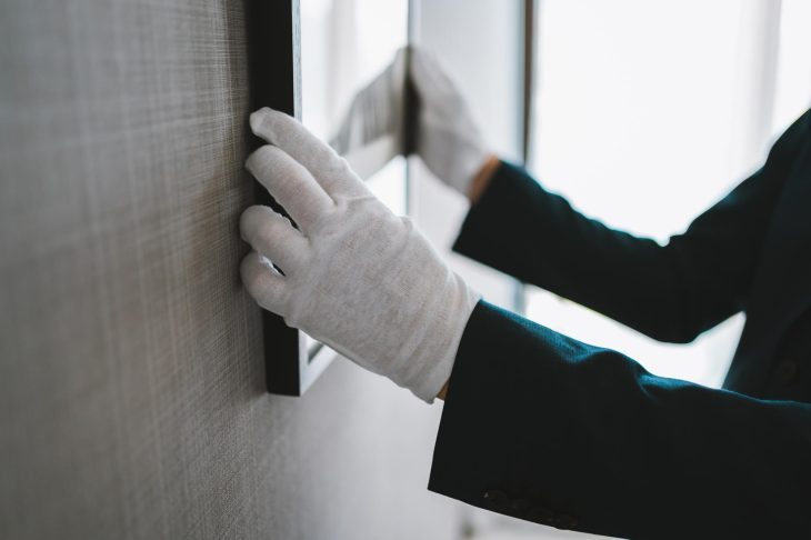 白い手袋をはめて絵画を扱う人物