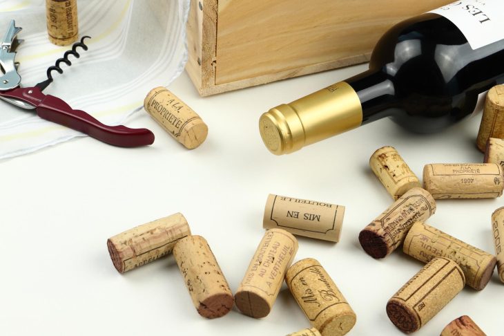 寝かせたワインボトルと複数のコルク