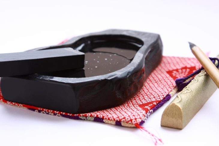 袱紗に乗った硯と墨、その横に置かれた筆置きと筆