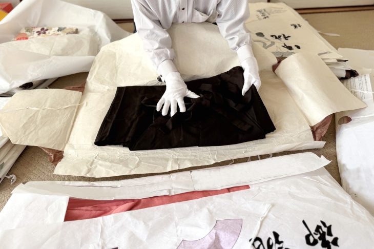 白い手袋を着用し着物を査定する人