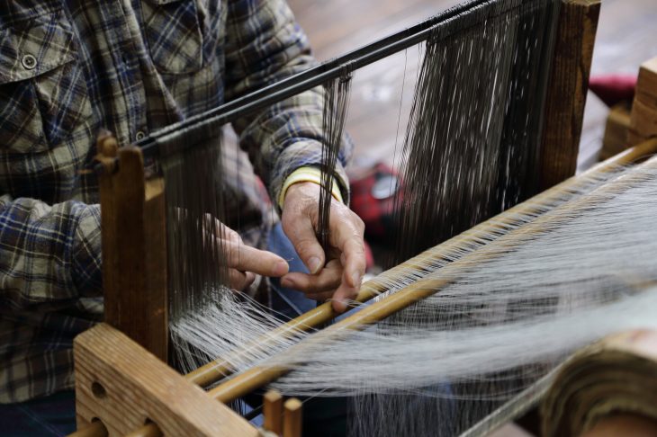 機織り機で生地を作る人の手