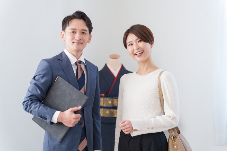 着物を前にほほ笑むスーツを着た男性と女性