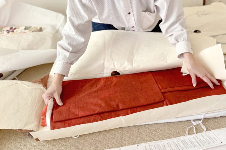 たとう紙に包まれた着物に触れる女性の手元