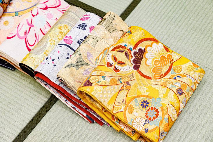 畳の上に並べられているさまざまな柄の着物や帯