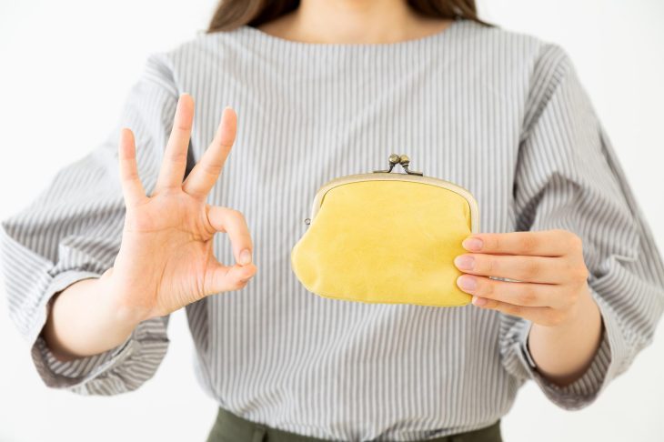 がま口財布を持ってOKサインを出す女性