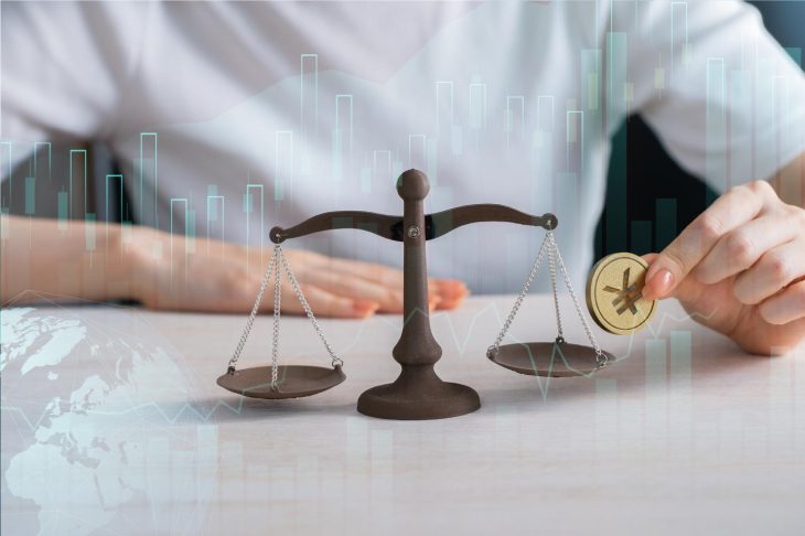 机の上に置かれたてんびんに金貨を1枚乗せようとする手元