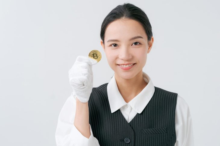 金貨を手に持ちほほ笑む白い手袋をはめた女性