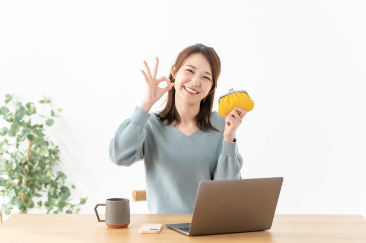 財布を片手にOKマークを作る笑顔の女性