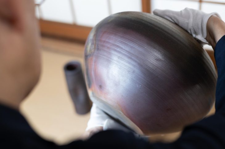 壺の側面を細かくチェックしている人