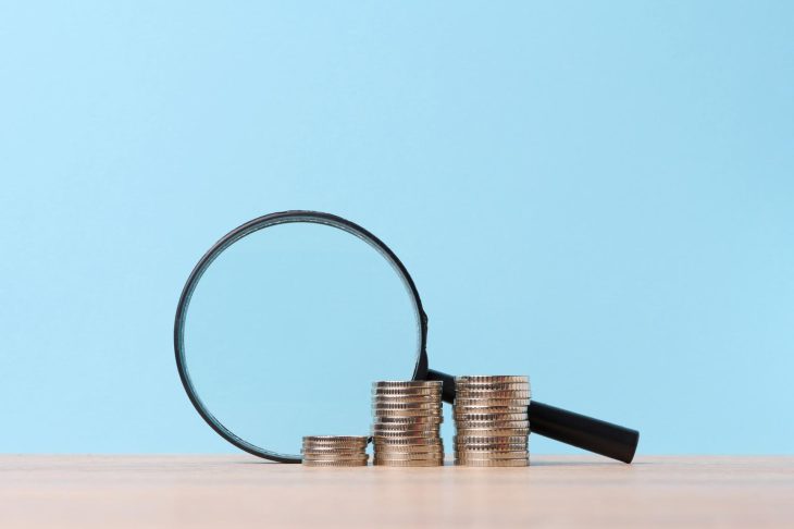 積まれたコインと虫眼鏡