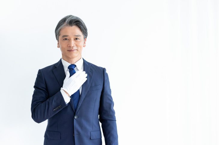 胸に手を当てる白い手袋の男性