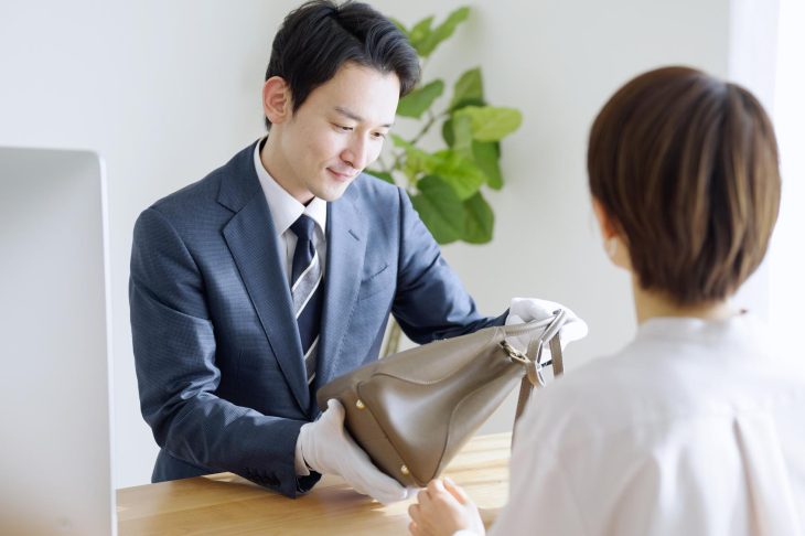バッグを細かくチェックしている査定士