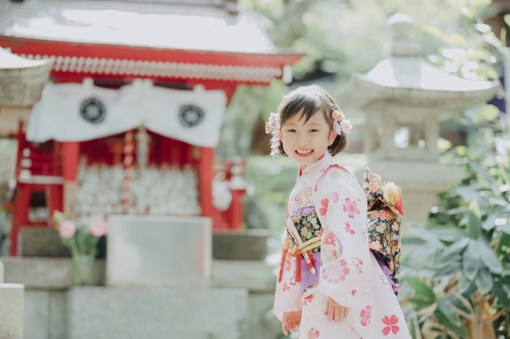 神社の前で写真を撮っている着物姿の女の子