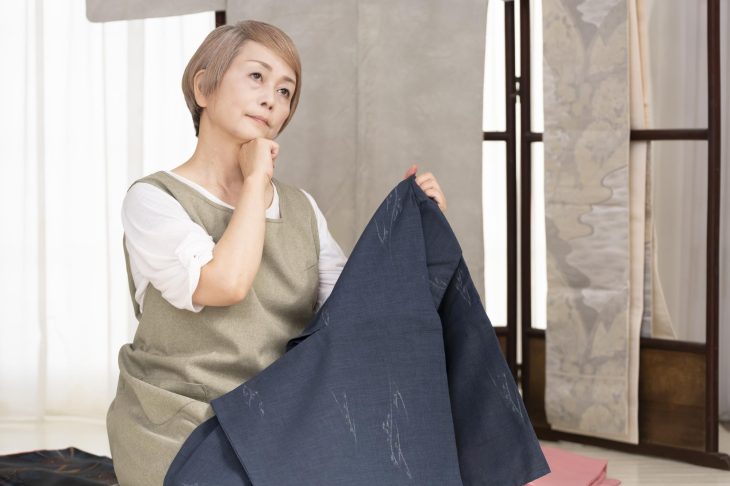着物を持って考え込む女性
