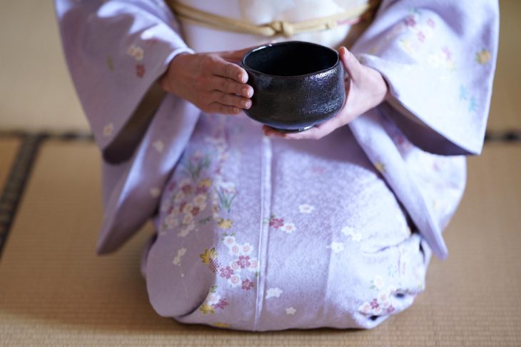 和室で正座した着物の人物が茶わんを持つ手元