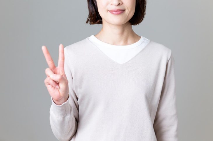 指で「2」を示すショートカットの女性
