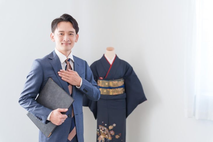 着物の前で胸に手を当てる男性査定士
