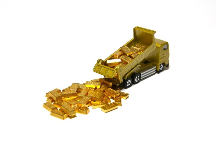 金色のダンプトラックのおもちゃから金の延べ棒が積み下ろされている