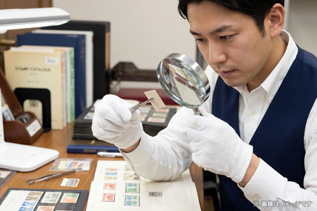 真剣に切手の査定を行う査定士のイメージ