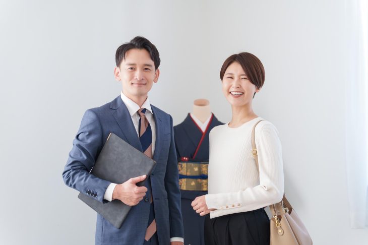 着物の前に並んで立つ査定士と女性