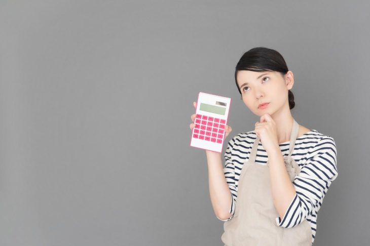 電卓を持って考え込んでいる様子の女性
