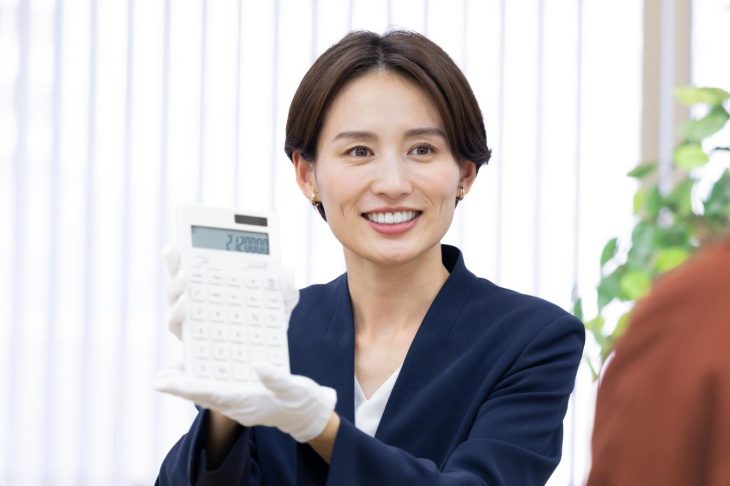 電卓に入力した数字を見せる査定士風の女性