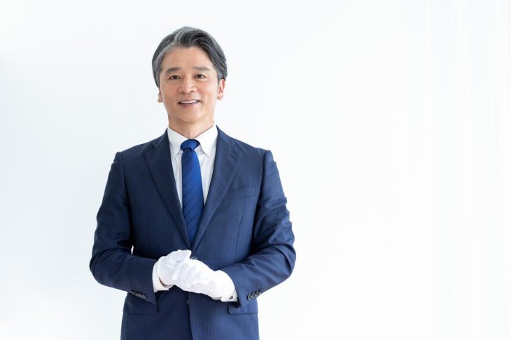 白い手袋をはめたスーツ姿の鑑定士風の男性