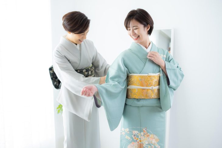 訪問着の着付けをする女性と着せてもらう女性