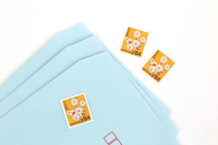 封筒と84円切手が並べられた郵便利用のイメージ