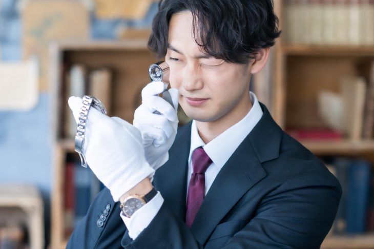 ルーペで腕時計を細かくチェックしている男性