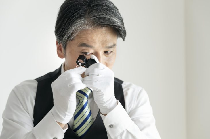 指輪をルーペで丁寧にチェックしている査定士