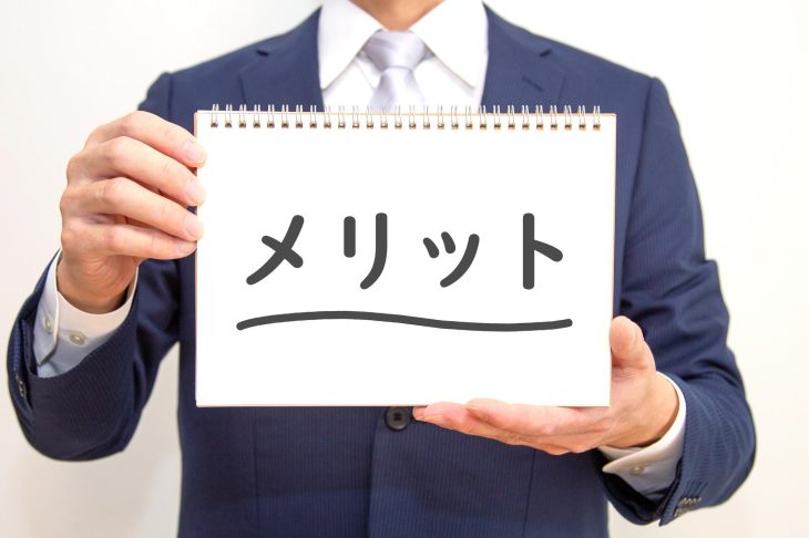 メリットと書かれたボードを持っている人