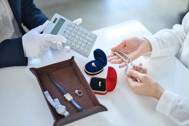 宝石や時計の査定が終了し、電卓で金額を提示される様子
