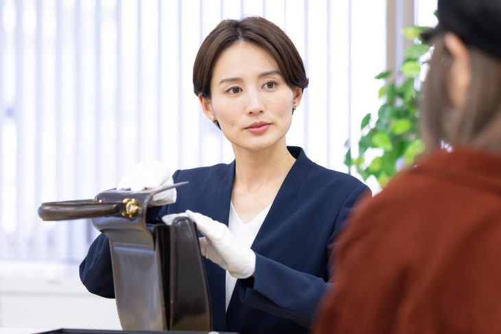 バッグを開けて確認する女性査定士と様子を見守る客
