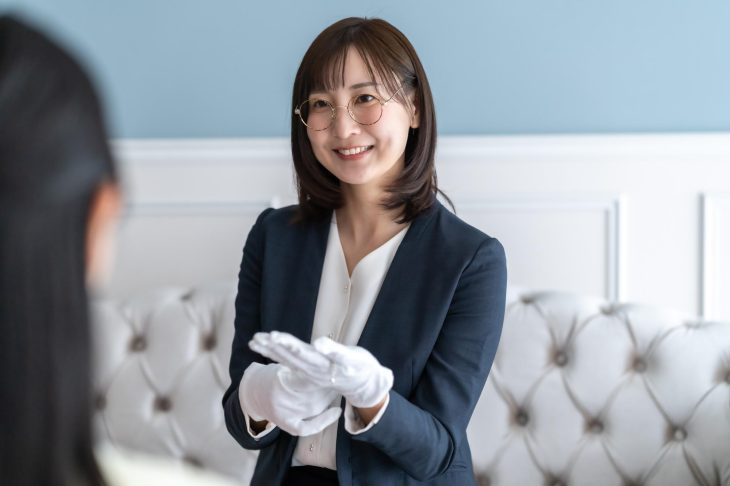 白手袋を着けた女性スタッフが、笑顔で接客している様子