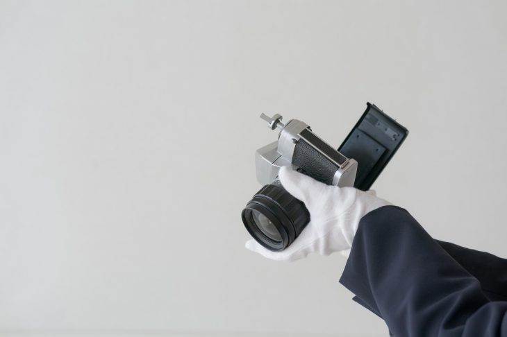白い手袋をはめて古いカメラを査定する様子
