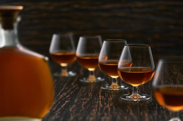 5つのグラスに注がれている酒とその前に置いてあるボトル