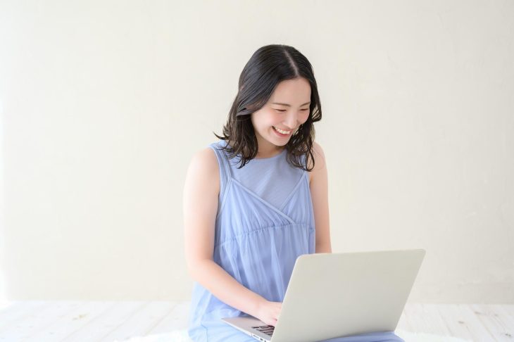 笑顔でノートパソコンを操作する女性
