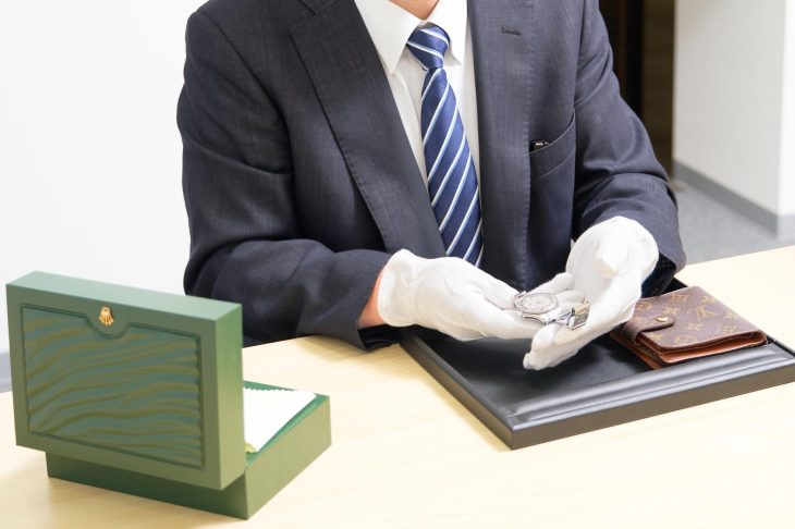 財布と腕時計をチェックしている査定士