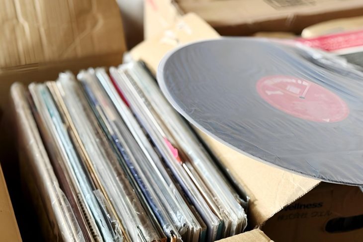 段ボール箱に立てて収納したレコードと、その上に平置きしたレコード盤